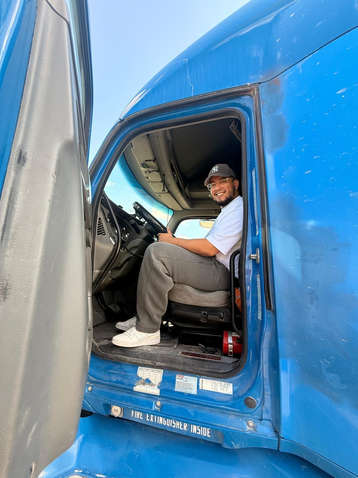 ABBA Global Corp driver smiling in the cab of a blue truck